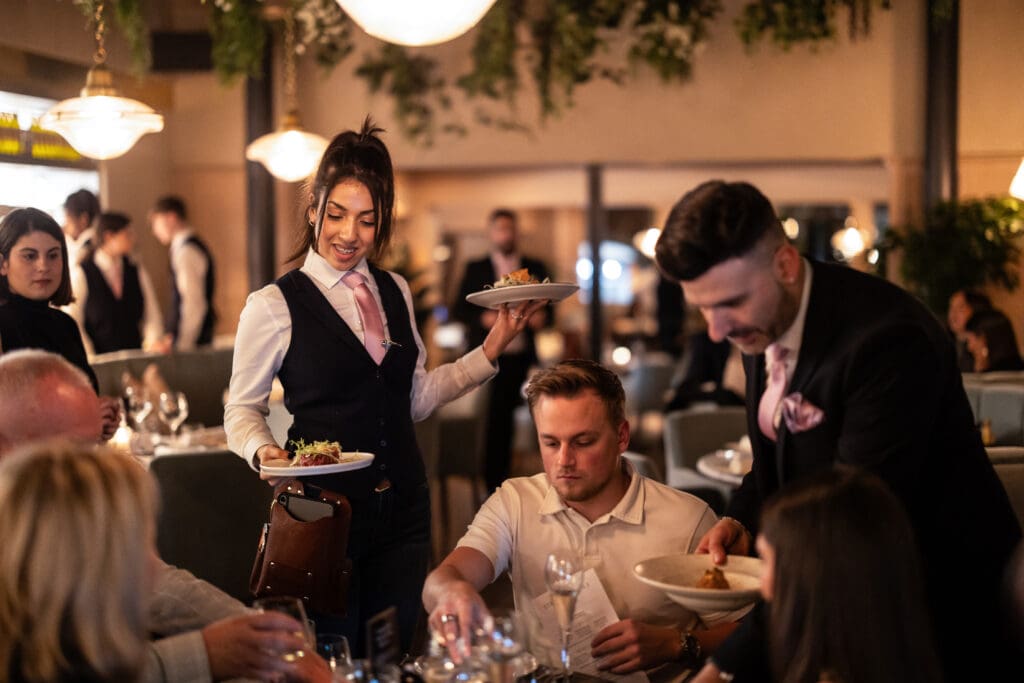 Waiters are serving food to a small group of people at Individual Restaurants