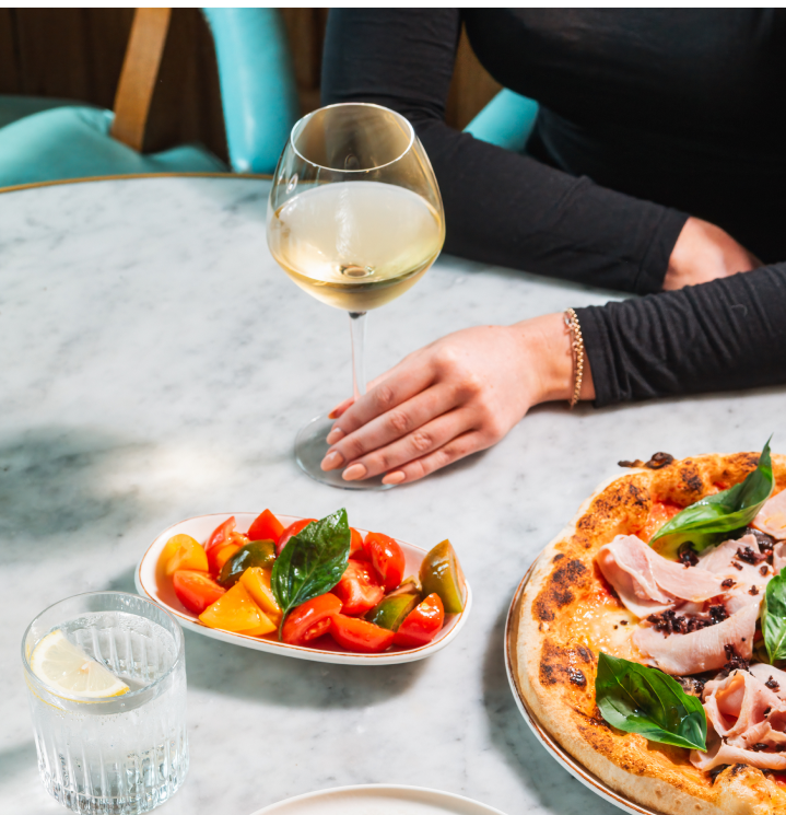 Pizza, tomatoes and white wine on a table